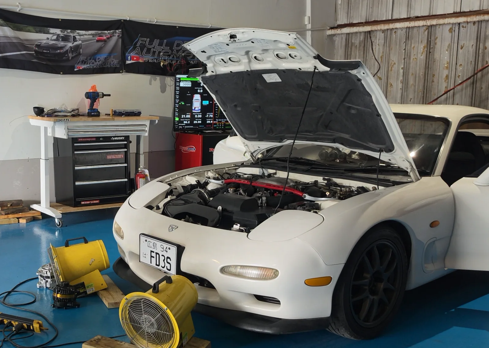 White Mazda RX-7 positioned in a workshop with airflow fans during testing